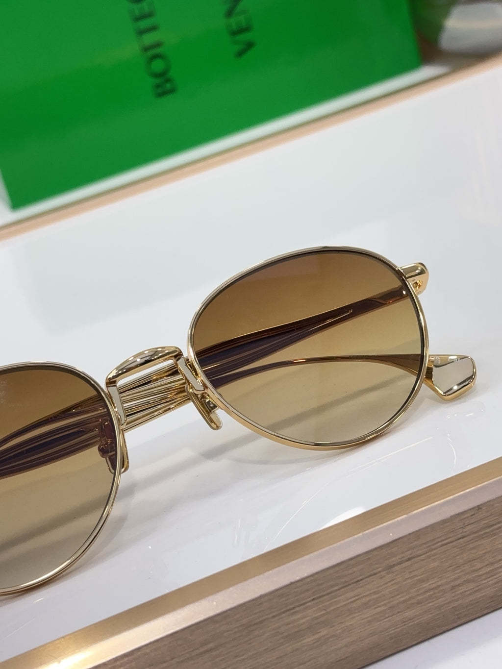 Bottega Veneta round sunglasses close-up, gold-tone frame with amber mirrored lenses