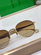 Bottega Veneta round sunglasses close-up, gold-tone frame with amber mirrored lenses