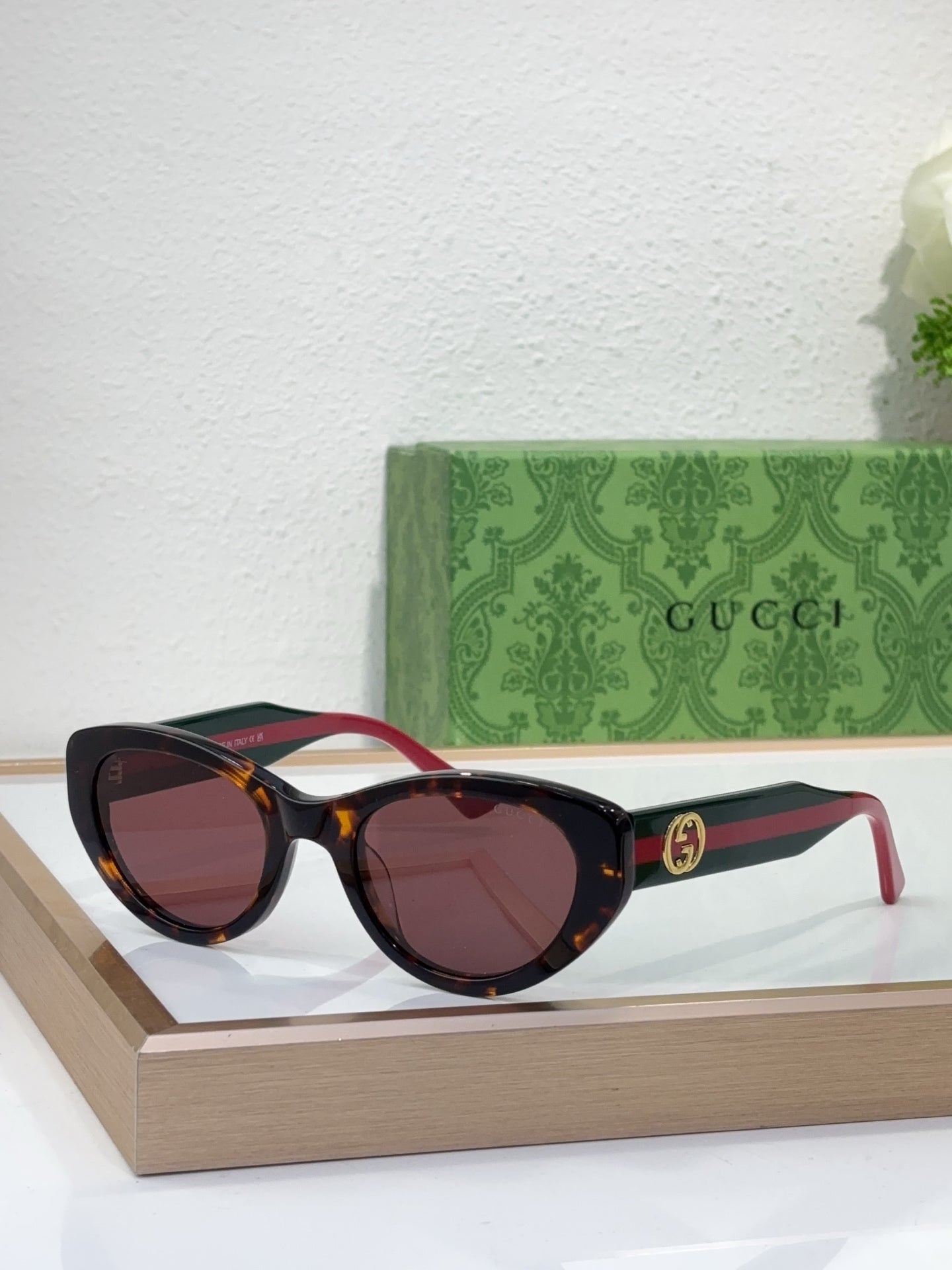 Sunglasses with black frame, warm brown tinted lenses, and red-and-black striped arms