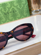 Sunglasses close-up with tinted lenses and red temple trim with GG logo