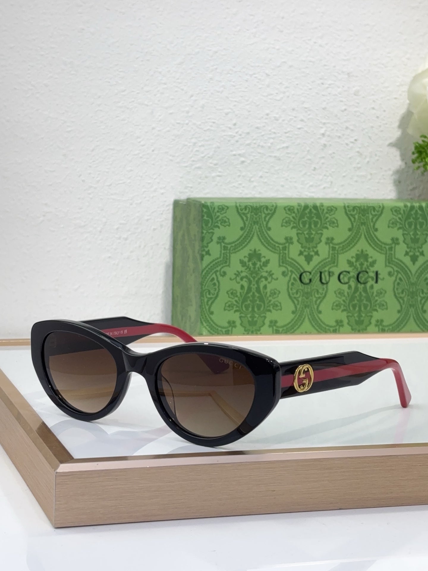 Sunglasses with black frame, gradient brown lenses, and red-and-black striped temples