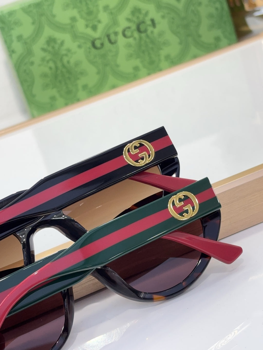 Sunglasses temple close-up with GG emblem on red-and-blue striped arm