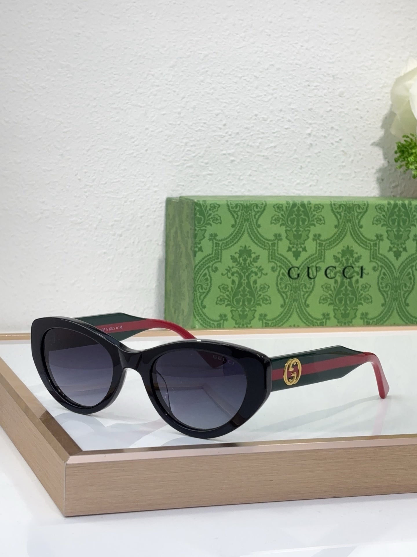 Sunglasses with black frame and tinted lenses, featuring red-and-black striped temples