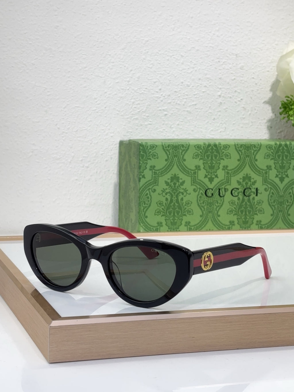 Gucci sunglasses with black frame, dark lenses, and red-and-black striped temples