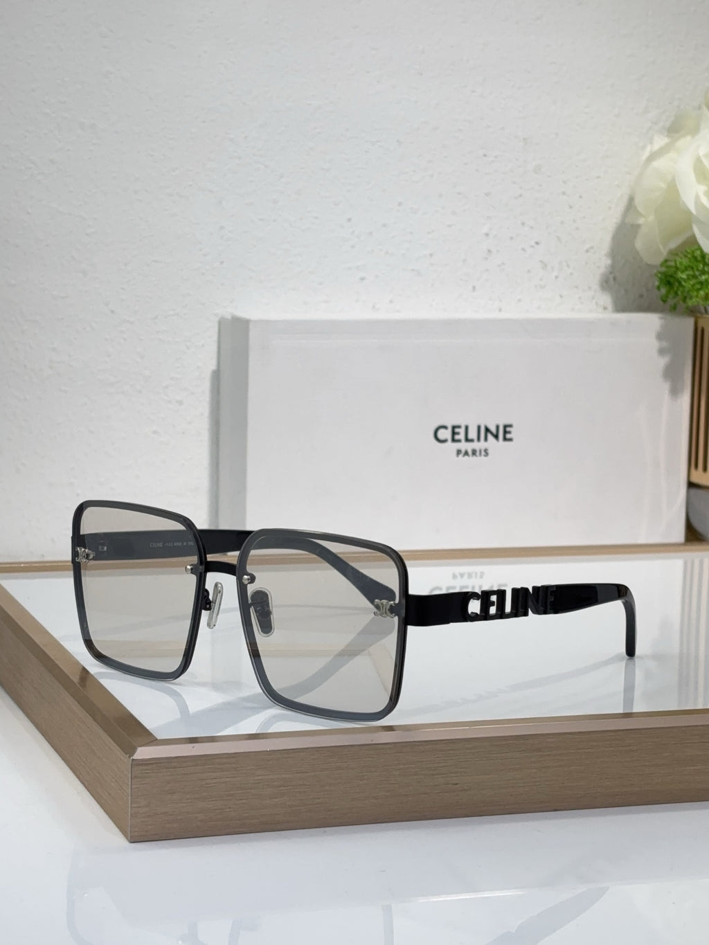 Sunglasses with dark-tinted lenses and black square frame, gold rivets