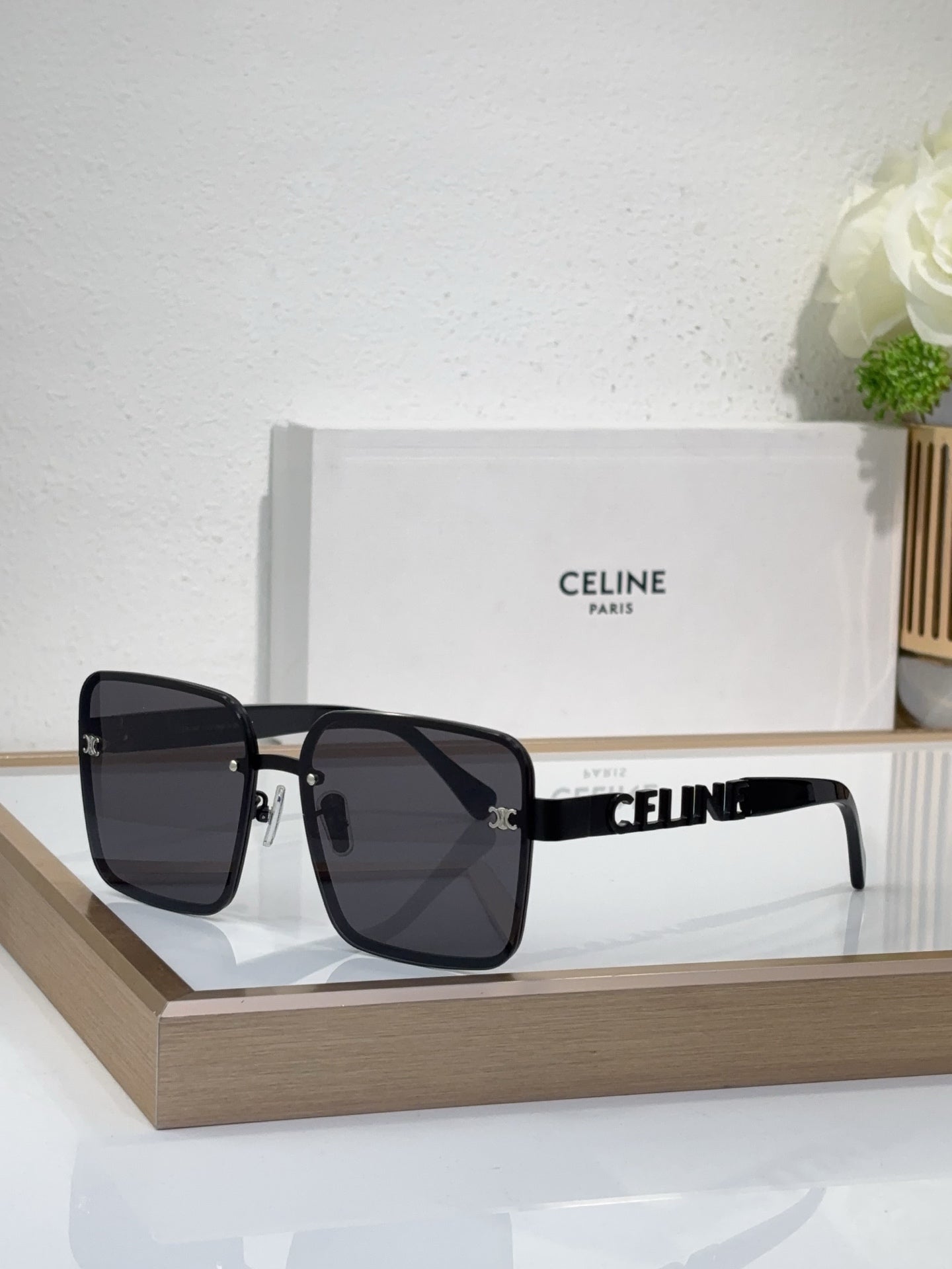Sunglasses with black oversized square frames and dark tinted lenses, gold hardware