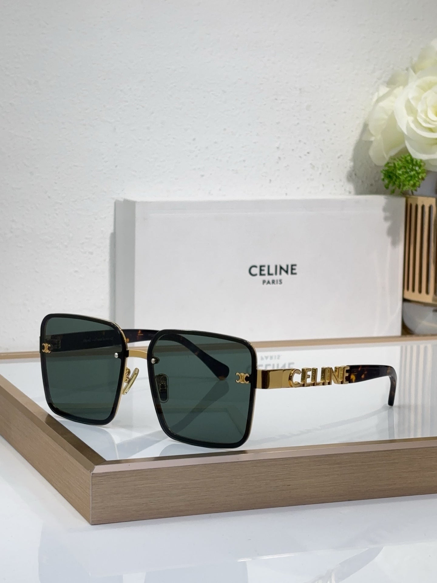 Sunglasses with black frames, dark gradient lenses, gold temple accents