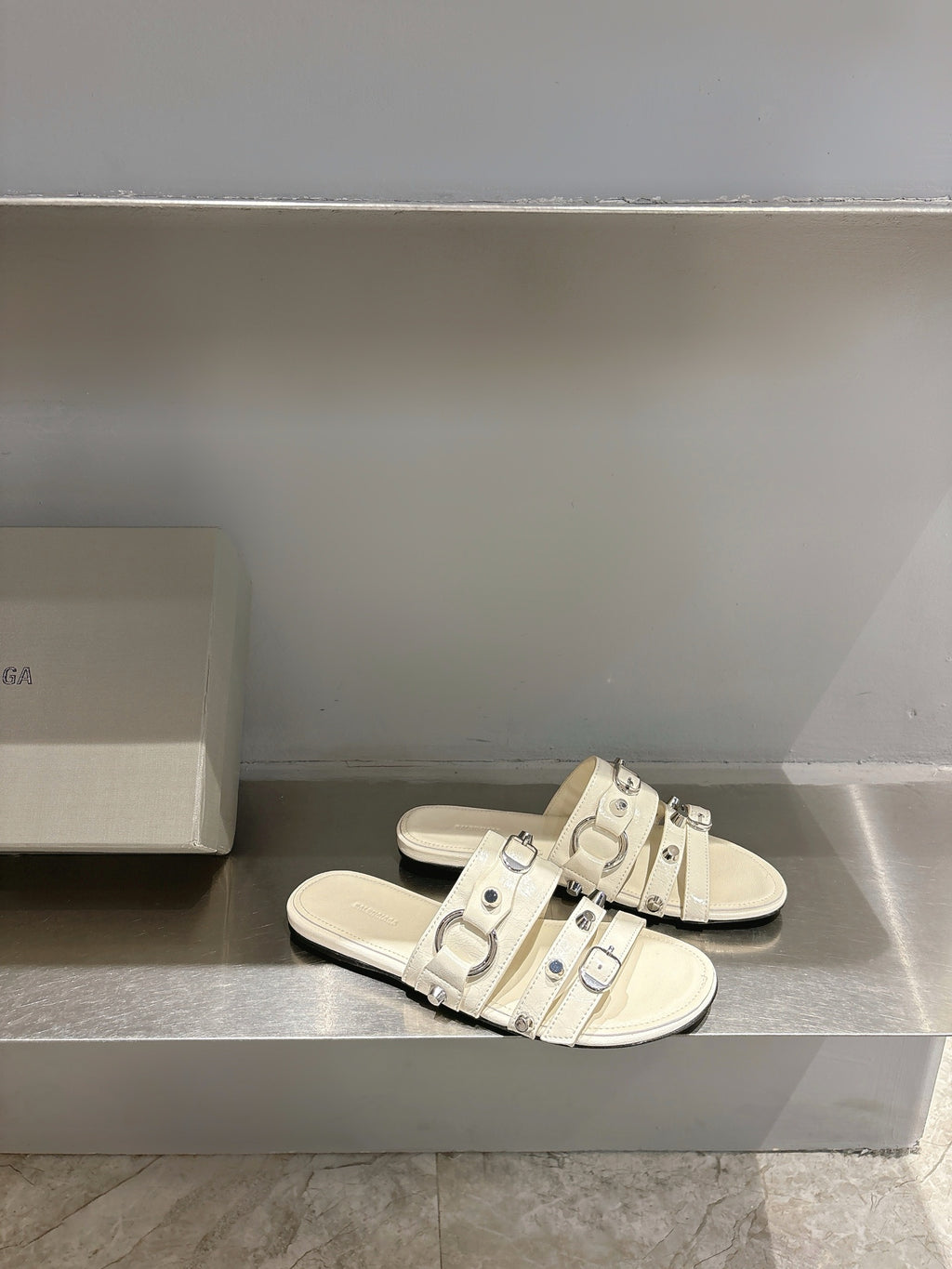 Balenciaga leather sandals in white with multiple buckle straps on flat slide sole.