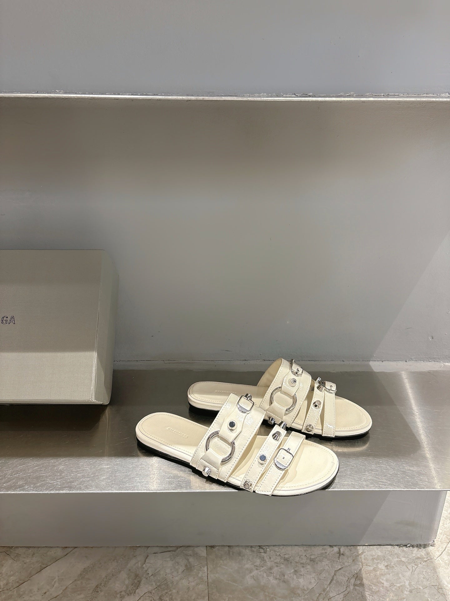 Balenciaga leather sandals in white with multiple buckle straps on flat slide sole.