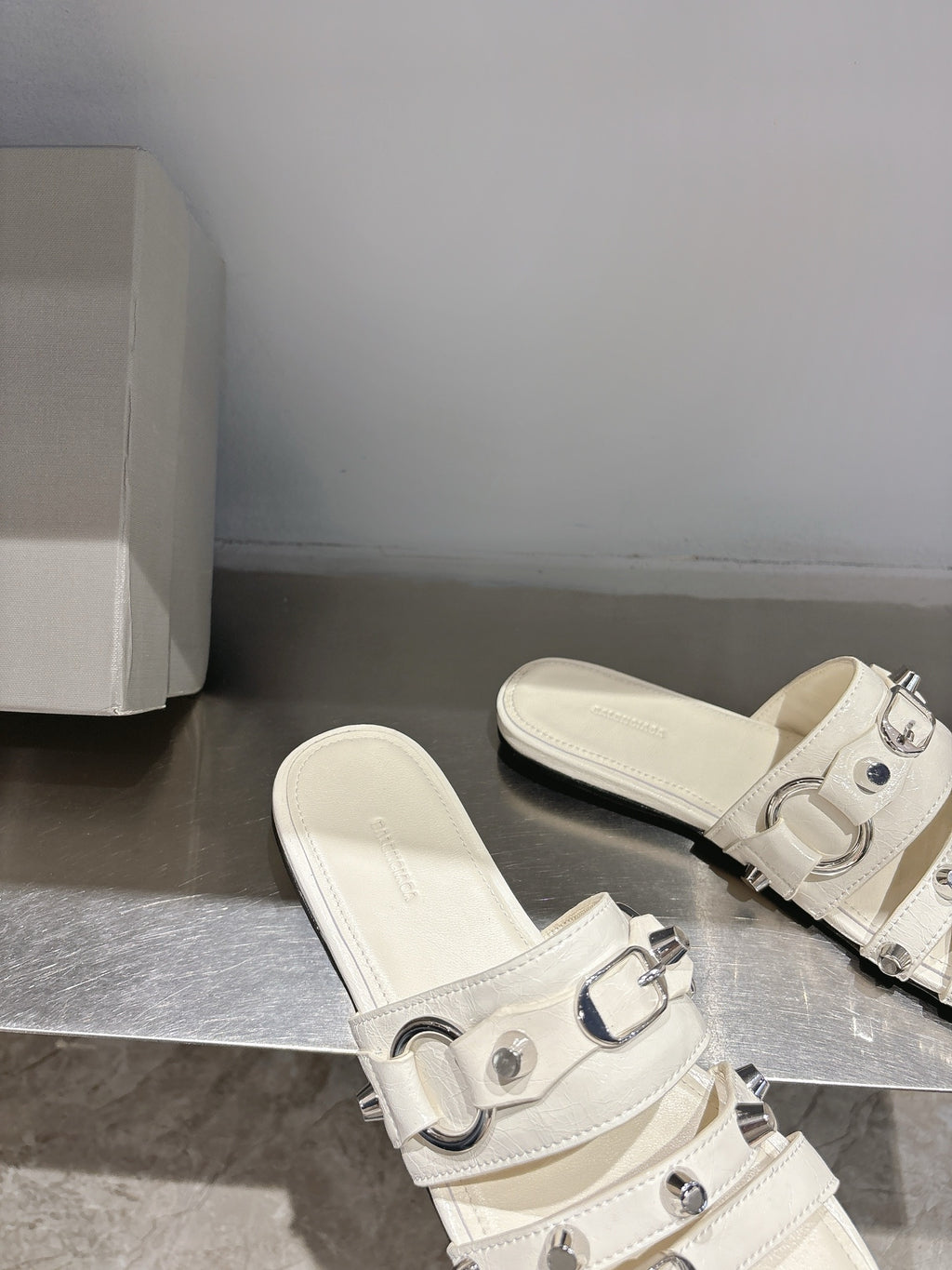 Balenciaga leather slip-on sandals in white with front buckles and open toe.