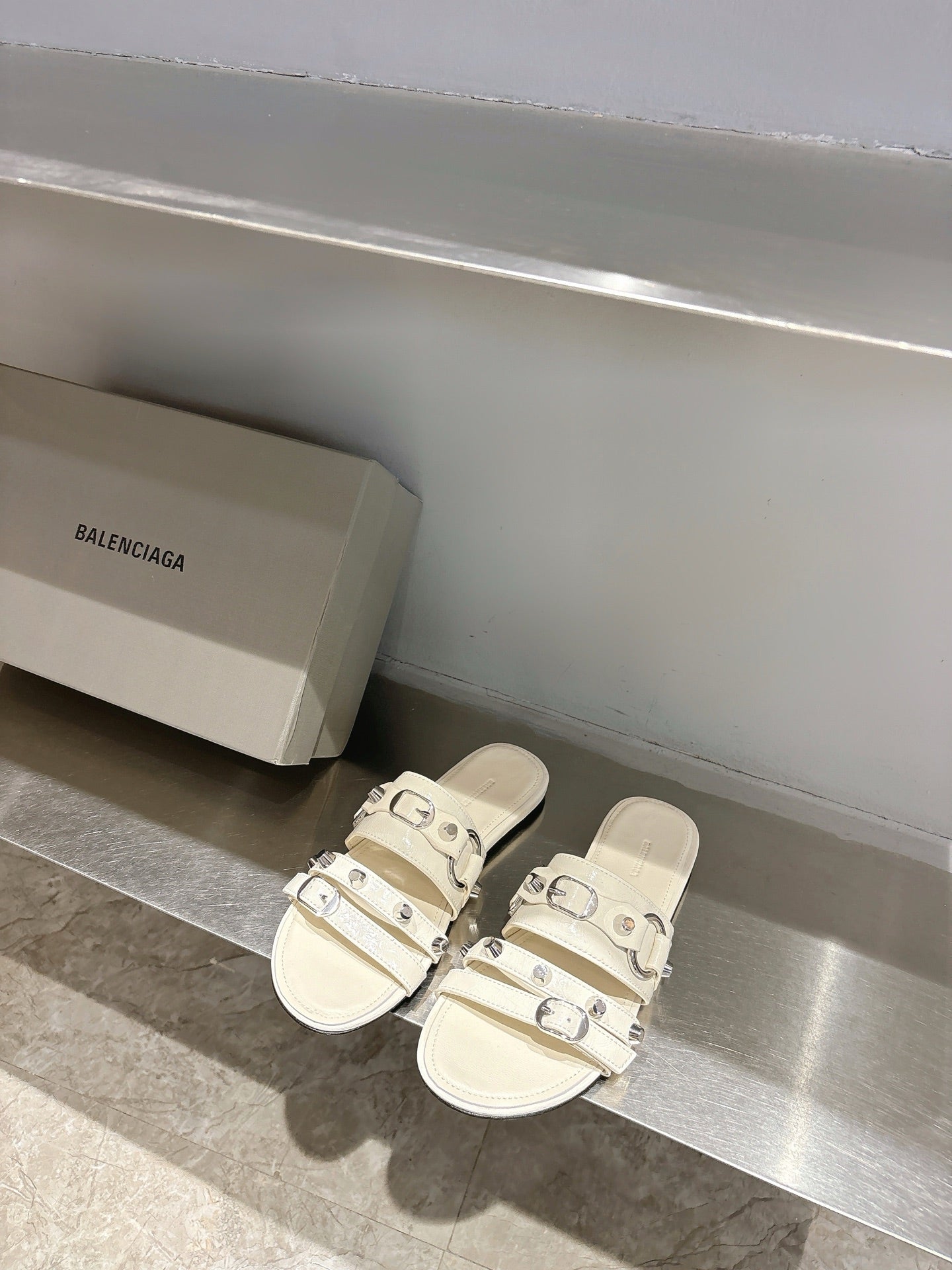 Balenciaga leather sandals in white with triple buckle straps on flat slide sole.