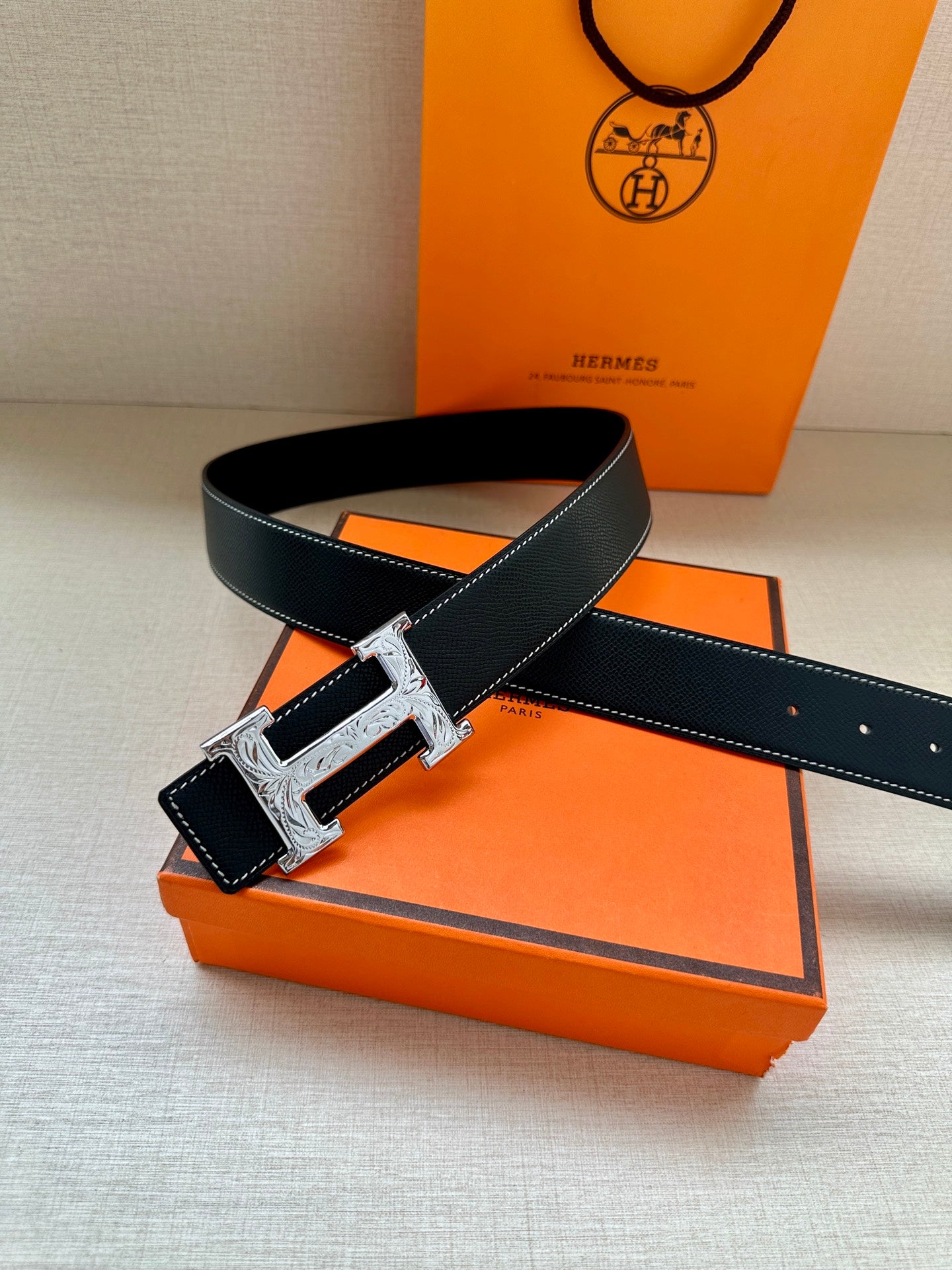 Dark blue leather belt with silver buckle and adjustable holes on orange tray