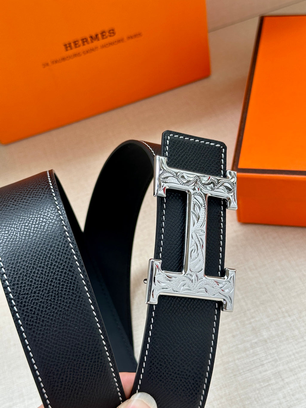Dark leather belt with silver-tone H buckle detail and textured strap