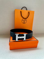 Dark leather Hermes-style belt with large silver-tone H buckle on box