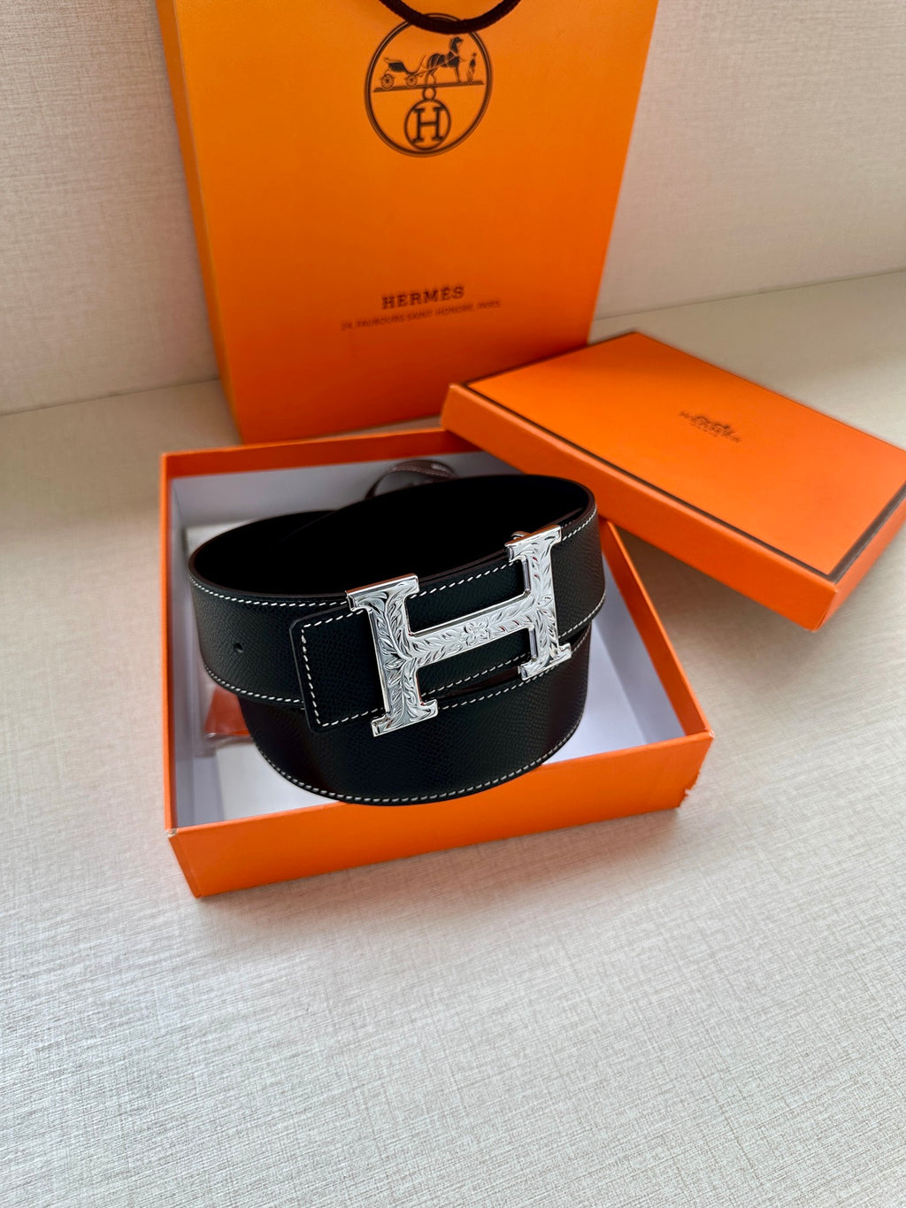 Dark leather Hermes belt with silver-toned H buckle on display