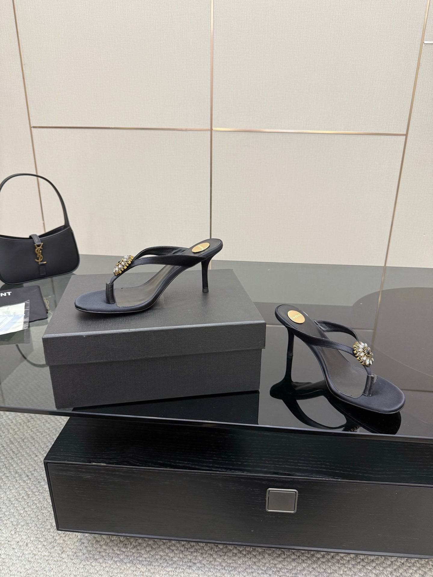 Women’s black high-heel thong sandals featuring a gold-toned jeweled toe detail.