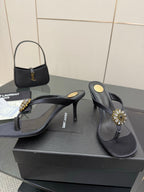 Women’s black high-heel thong sandals with gold-toned jeweled ornament and slim heel.