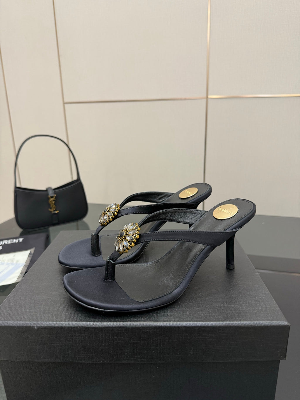 Women’s black heeled flip-flop sandals with jeweled gold-toned toe and side straps.