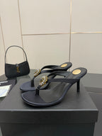 Women’s black heeled flip-flop sandals with jeweled gold-toned toe and side straps.