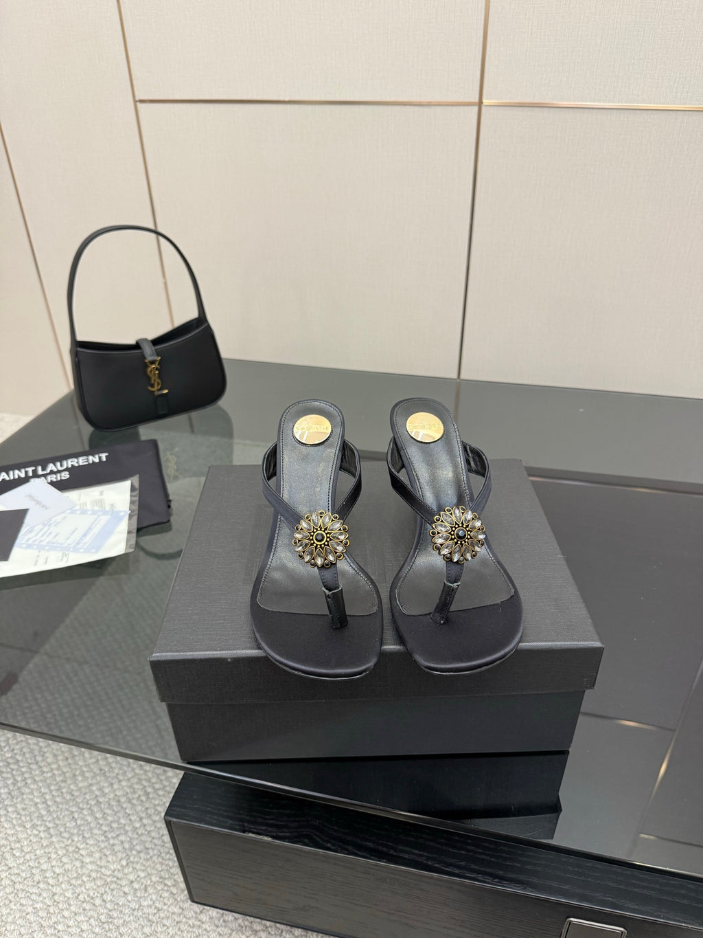 Women’s black high-heel thong sandals on a box with gold-toned jeweled toe embellishments.