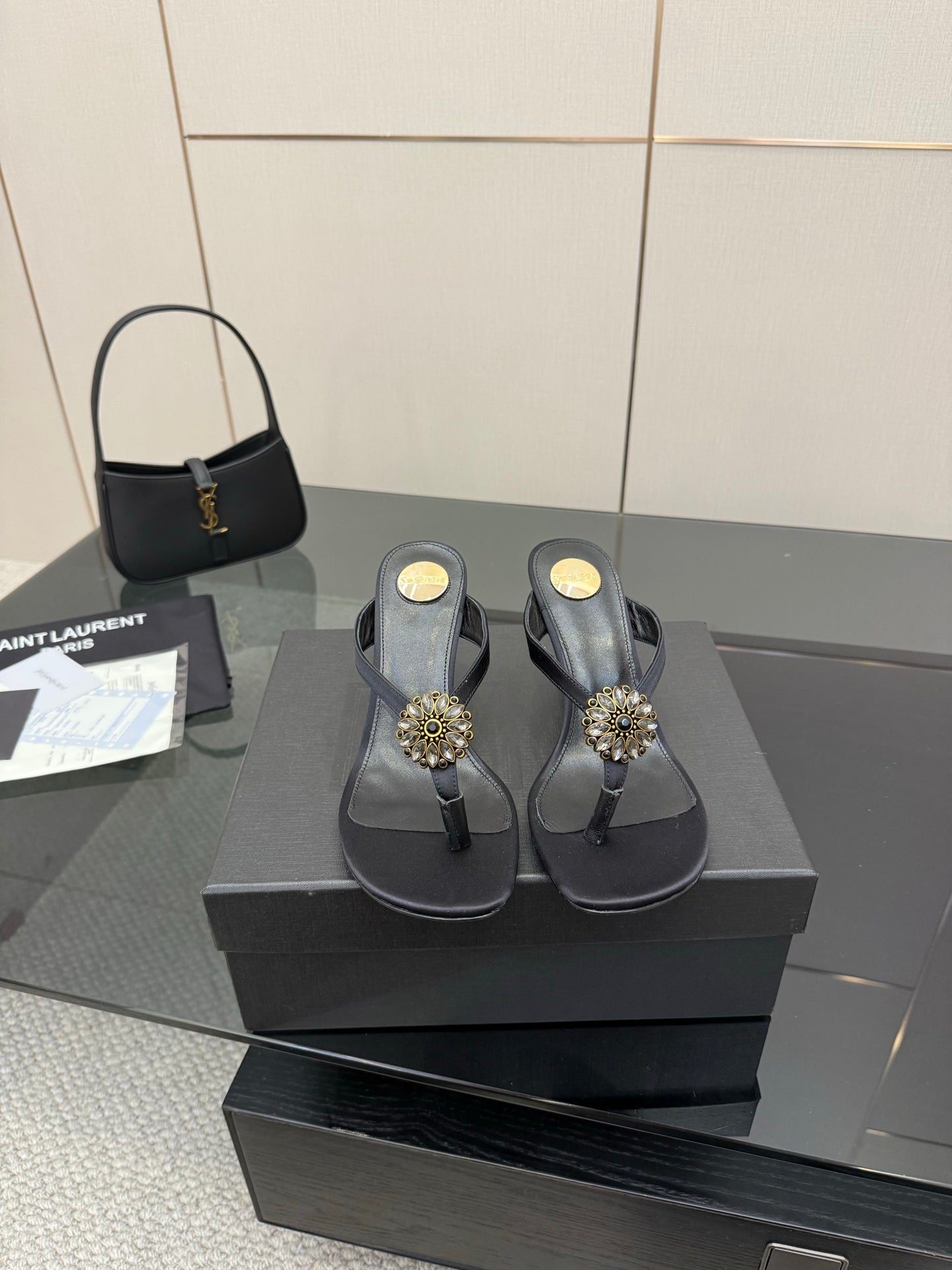 Women’s black high-heel thong sandals on a box with gold-toned jeweled toe embellishments.
