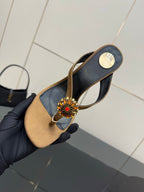 Handheld thong heeled sandal with black straps, tan footbed, and jeweled flower