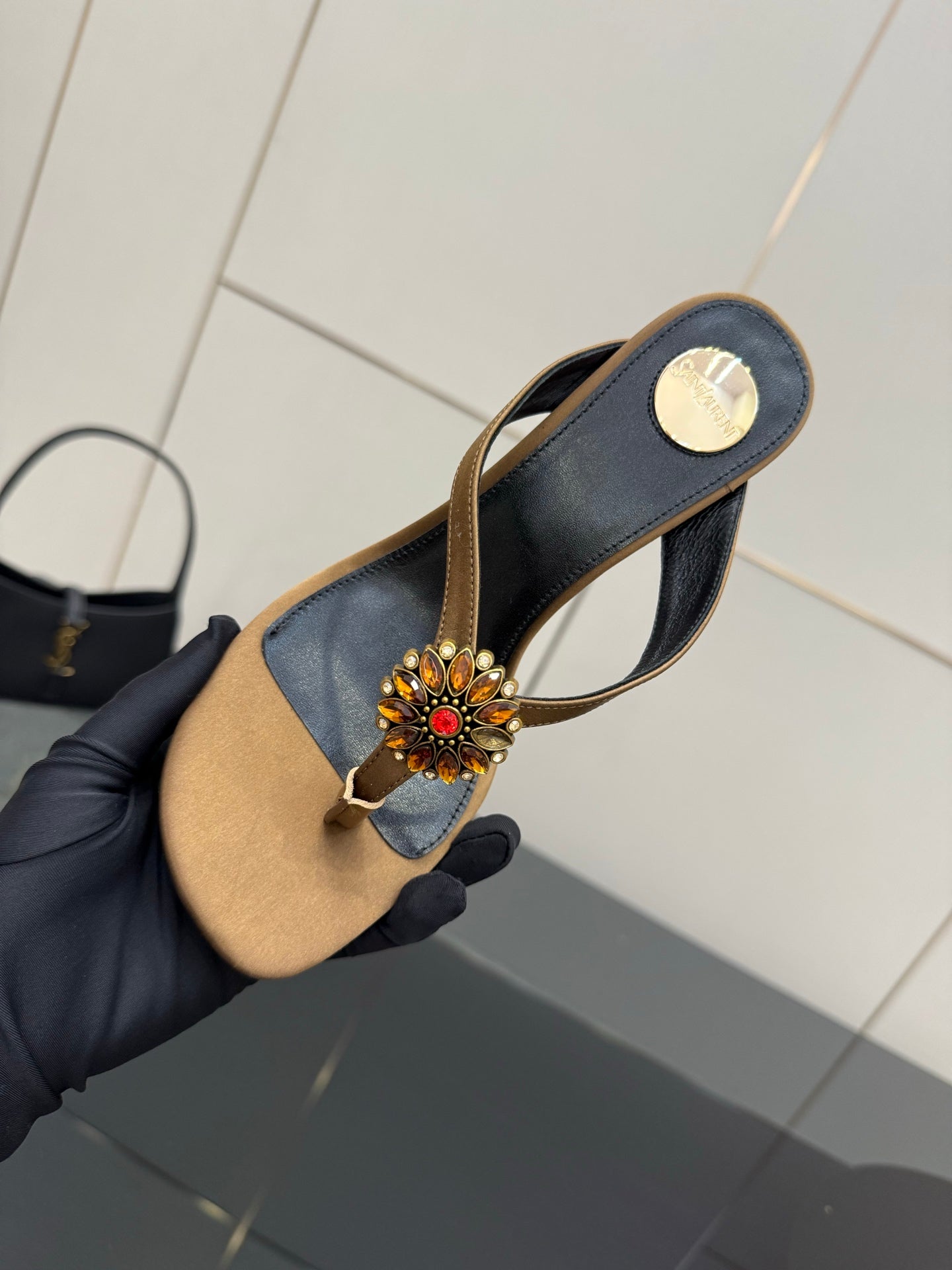 Handheld thong heeled sandal with black straps, tan footbed, and jeweled flower