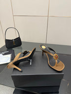 Side view of thong heeled sandals with tan footbed, black straps, jeweled flower