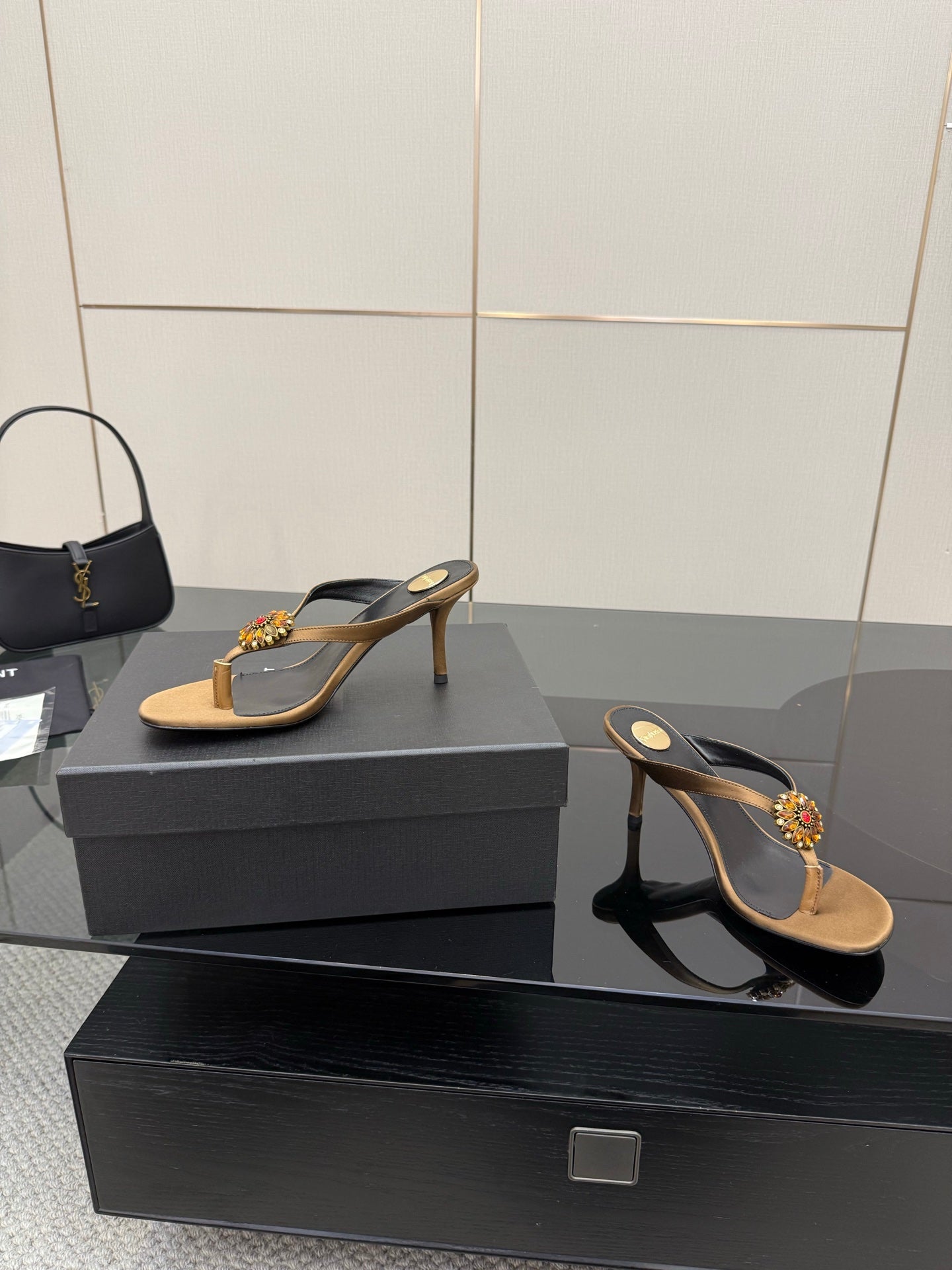 Thong heeled sandals showing black heel strap and tan toe strap with jewel flower