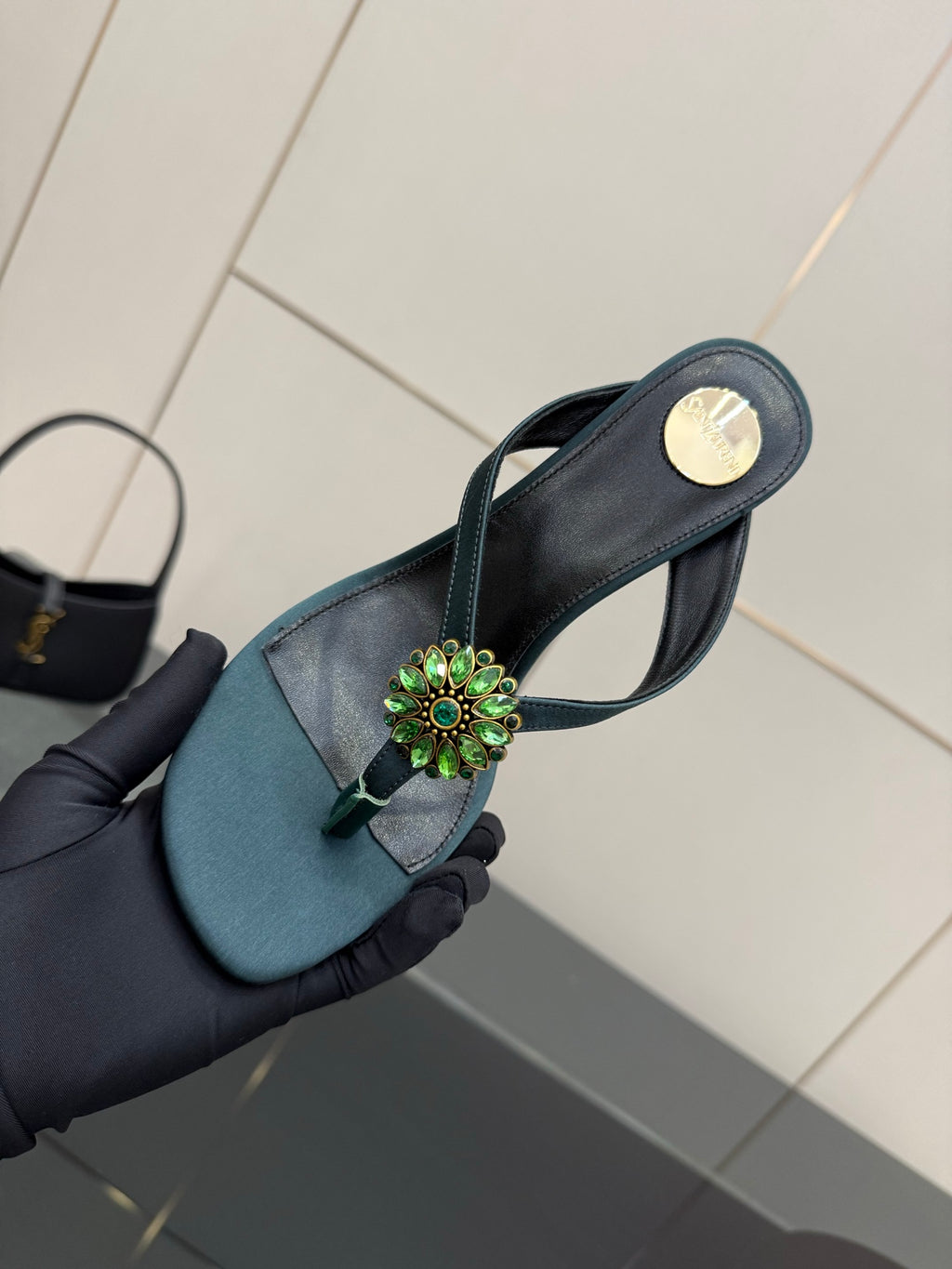 Women's teal heeled sandal close-up with jeweled floral strap ornament
