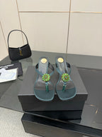 Pair of women's teal heeled sandals with jeweled floral center strap detail