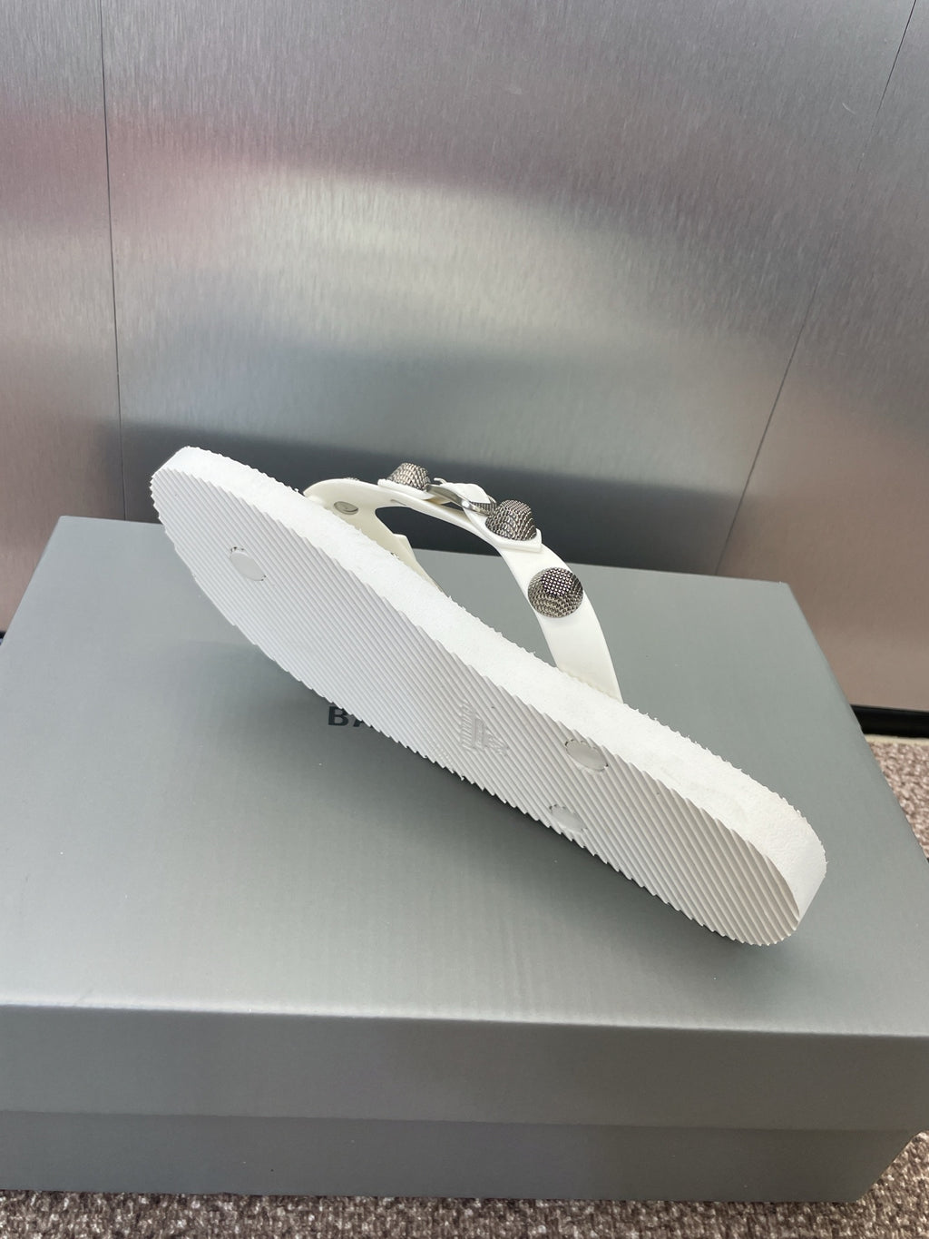 White thong sandal with studded straps and silver-tone hardware, angled