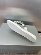 White thong sandal with studded straps and silver-tone hardware, angled