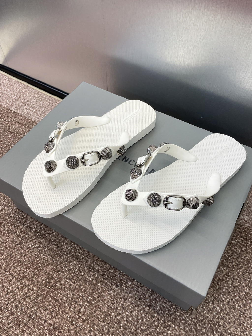 White thong sandals with bead-like studs and metallic buckles, side view