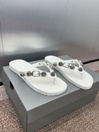 White thong sandals on box with studded straps and silver-tone hardware