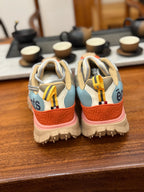 Back view sneakers with light blue heel, orange sole edge and yellow pull tabs