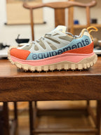 Light gray mesh sneakers with orange heel panel and pink midsole