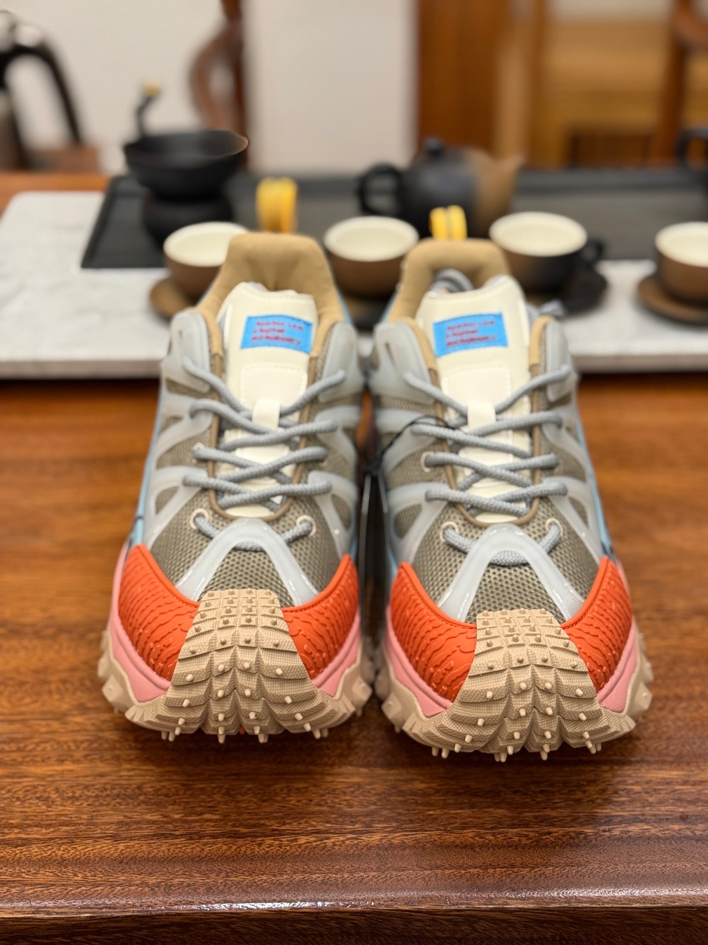 Light gray mesh sneakers with orange toe and heel, white laces