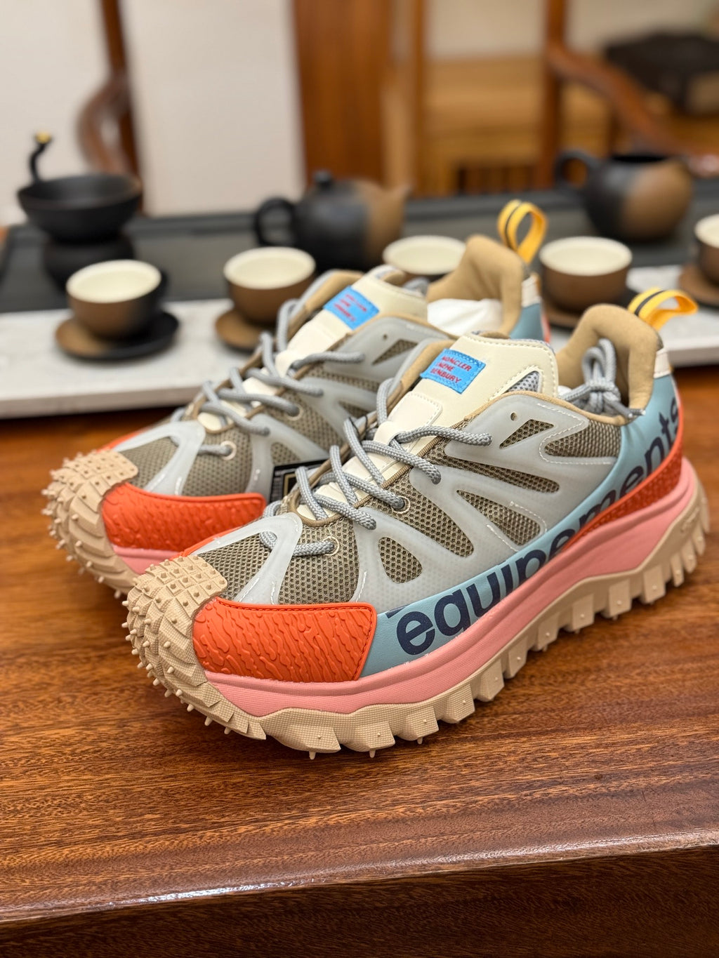 Light gray mesh sneakers with orange side panels and chunky tread sole