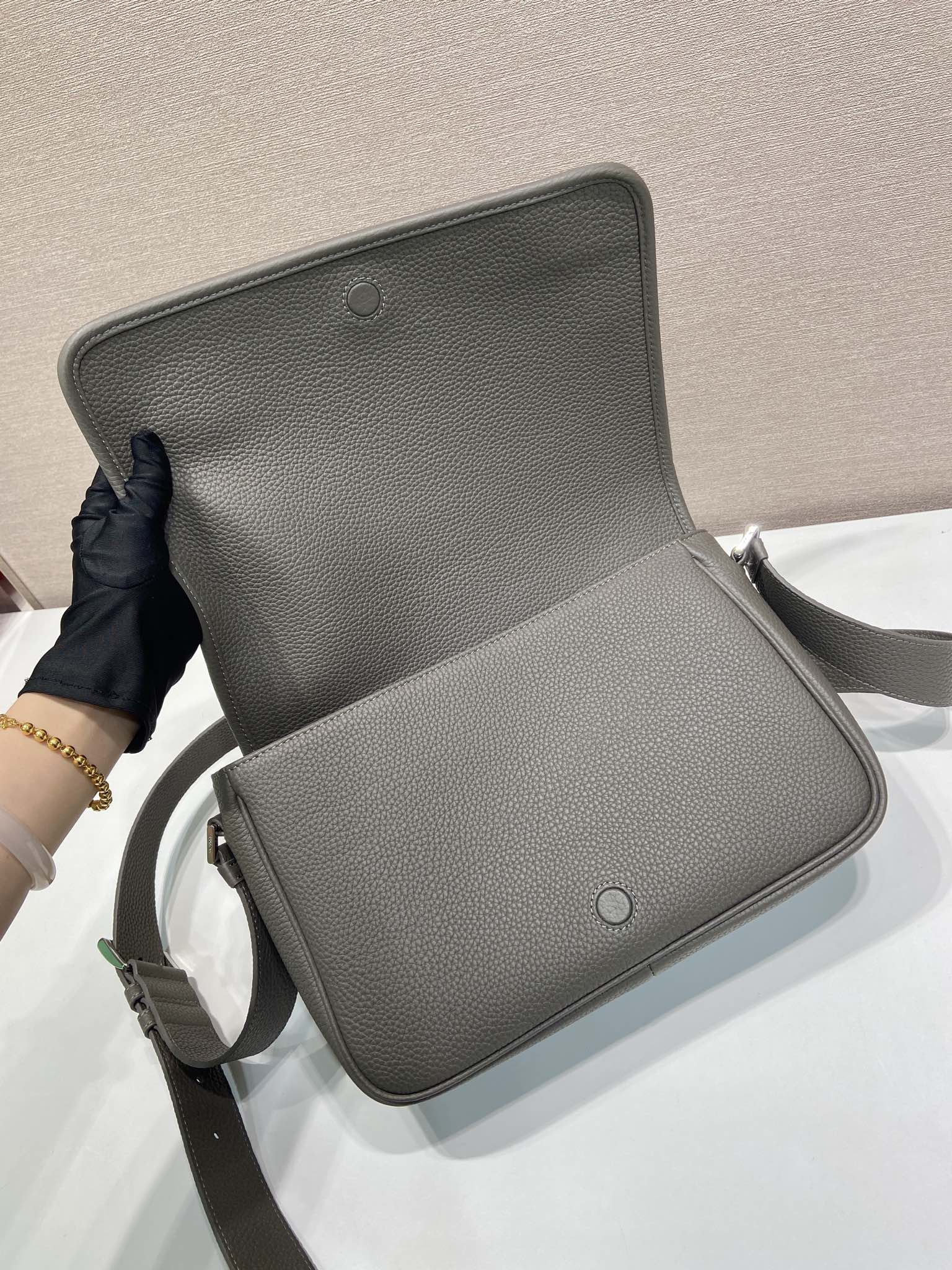 Prada leather crossbody bag open flap showing interior and magnetic closure button