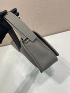 Prada leather crossbody bag worn on shoulder with adjustable strap and flap pocket