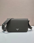 Prada leather crossbody bag with flap, top handle strap, and triangular logo plaque