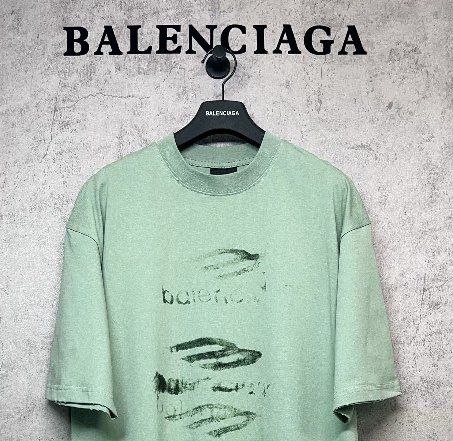 Mint green crew-neck graphic T-shirt with abstract logo print, short sleeves.