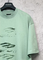 Mint green crew-neck T-shirt with partial graphic logo print, short sleeves.