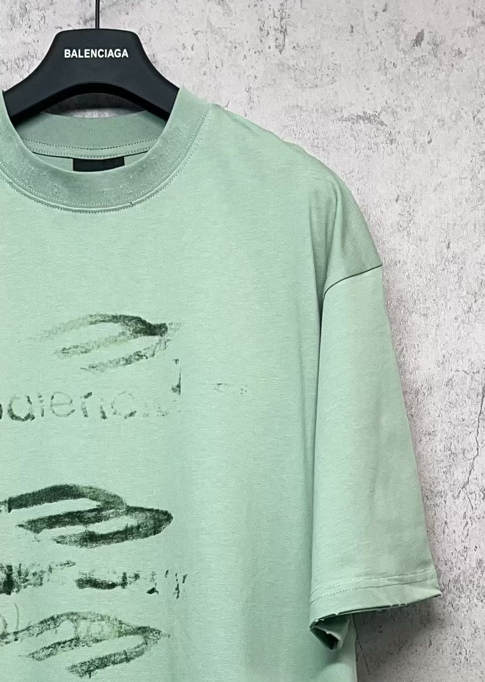 Mint green crew-neck T-shirt with partial graphic logo print, short sleeves.