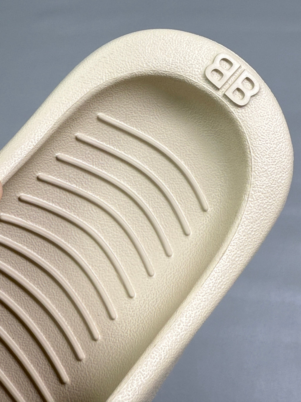 Cream sandal footbed close-up with embossed logo and textured traction ridges