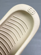 Cream sandal footbed close-up with embossed logo and textured traction ridges
