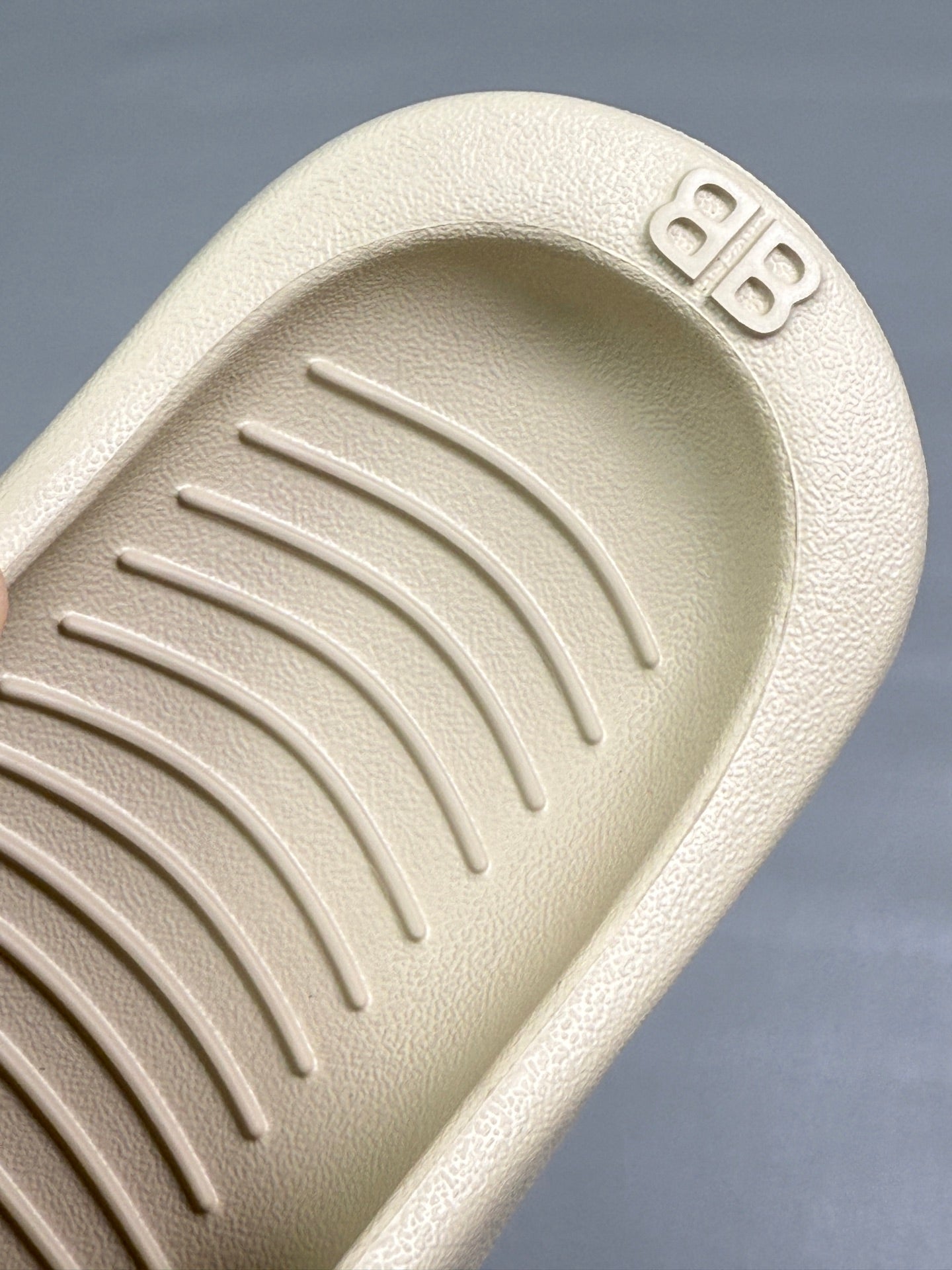 Cream sandal footbed close-up with embossed logo and textured traction ridges