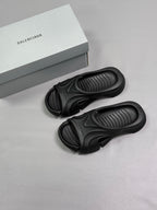 Two black Balenciaga slide sandals with the logo box nearby