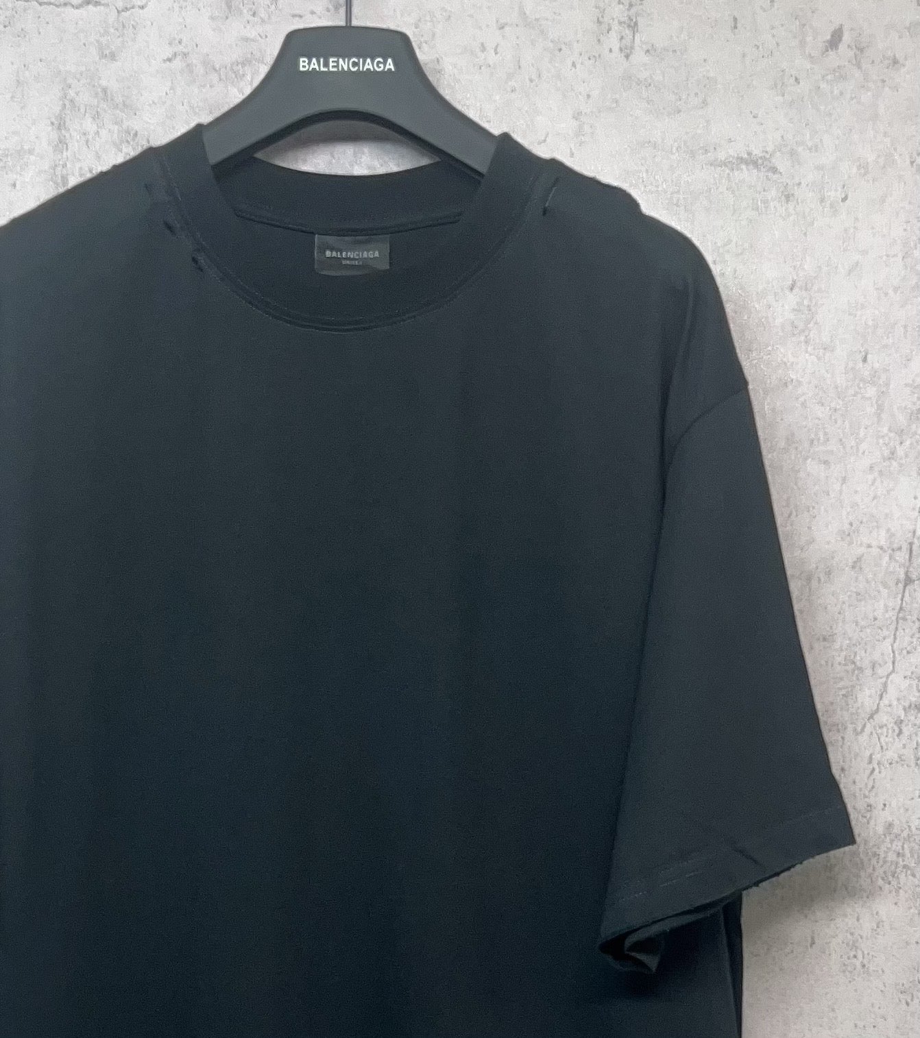 Black Balenciaga T-shirt side angle on hanger, short sleeves and crew neck.
